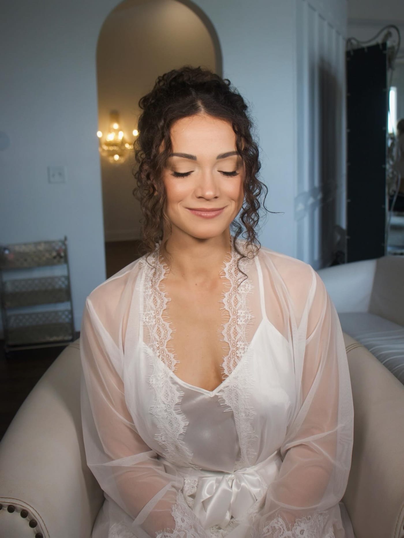 Bride in a lace getting-ready robe with a soft neutral eye and glossy lip