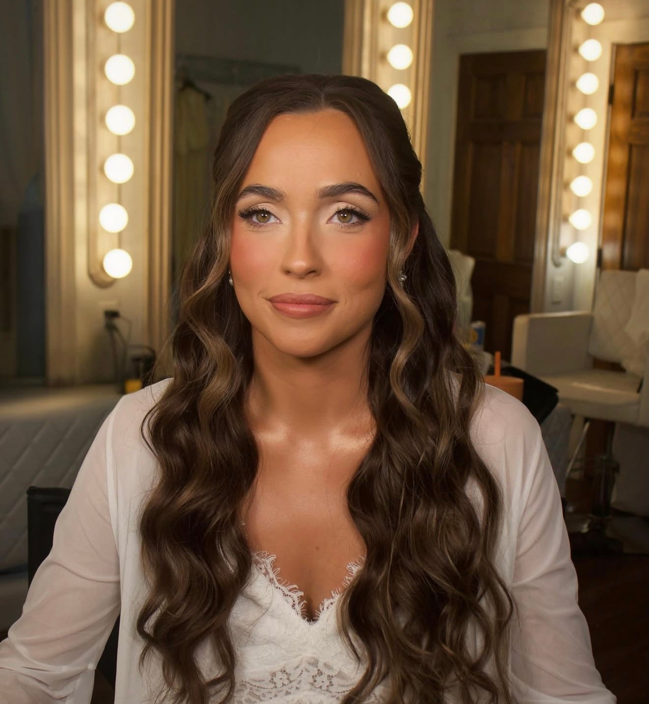 Bride at the vanity with a defined eye, sculpted cheek and long waves